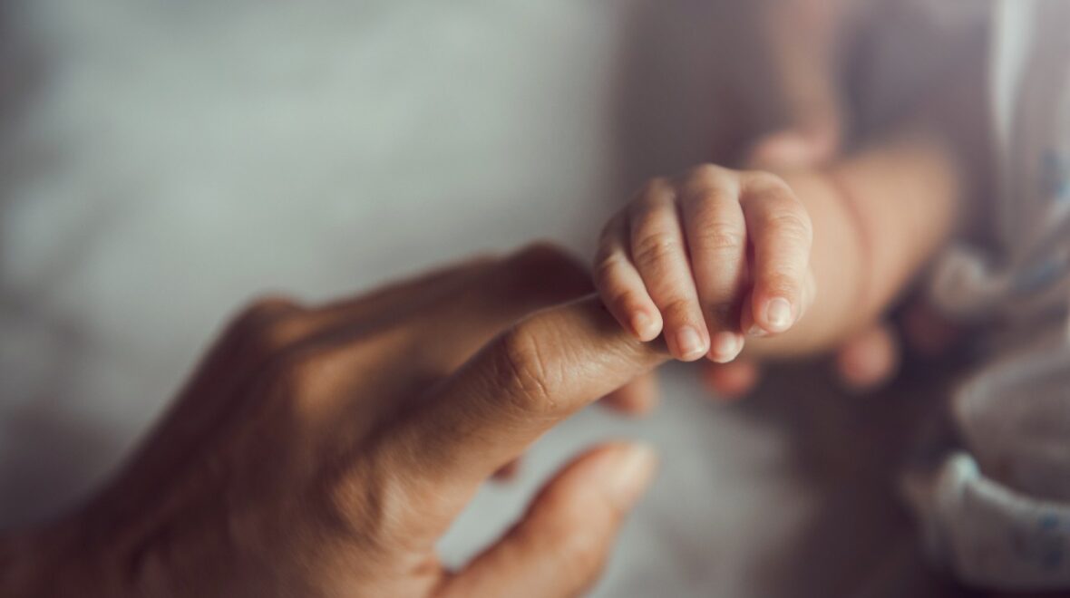Nyfödd håller i förälders hand